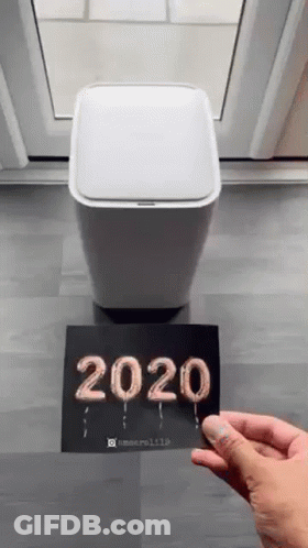 A Person Is Holding A Card That Says `` 2020 '' Next To A Trash Can . GIF