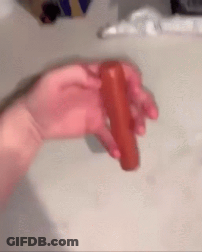 A Person Is Holding A Carrot In Their Hand On A Table . GIF