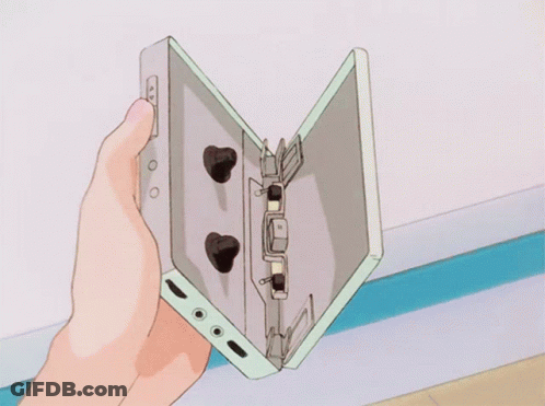 A Person Is Holding A Cassette Tape In Their Hand GIF
