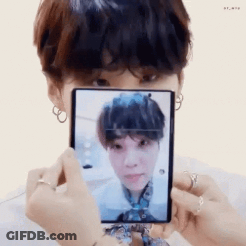A Person Is Holding A Cell Phone In Front Of Their Face And Taking A Picture Of A Person . GIF