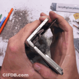 A Person Is Holding A Cell Phone In Their Hands With Jerry Rig Everything Written On A Tube In The Background GIF