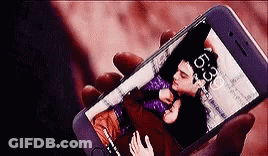 A Person Is Holding A Cell Phone With A Picture Of A Man And A Woman On The Screen . GIF
