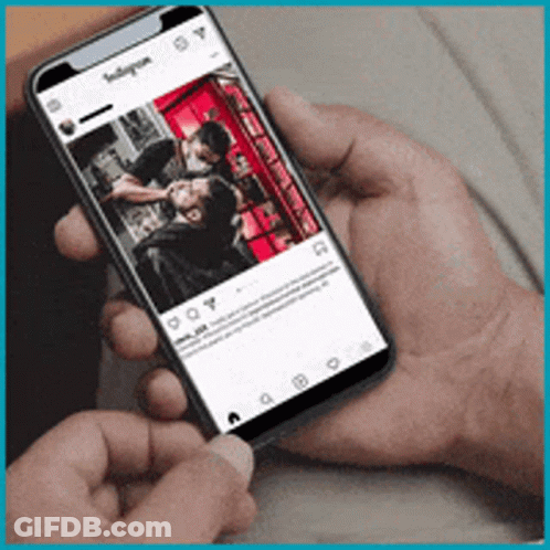 A Person Is Holding A Cell Phone With A Picture Of A Man Getting A Haircut On It GIF