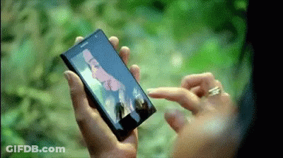 A Person Is Holding A Cell Phone With A Picture Of A Man On The Screen GIF