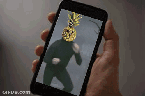 A Person Is Holding A Cell Phone With A Pineapple On Their Face GIF