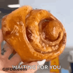 A Person Is Holding A Cinnamon Roll In Their Hand And Waiting For You . GIF
