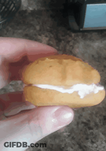 A Person Is Holding A Cookie With Whipped Cream On Top GIF