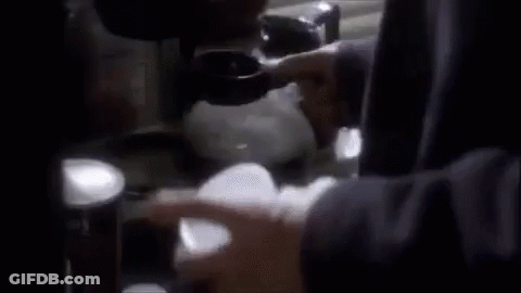 A Person Is Holding A Cup In Their Hand In Front Of A Stove . GIF