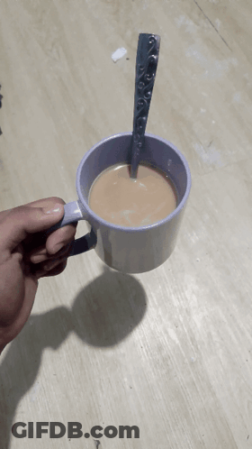 A Person Is Holding A Cup Of Coffee With A Spoon Sticking Out Of It GIF