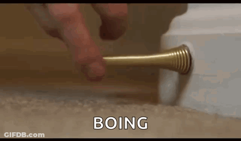 A Person Is Holding A Door Stop In Their Hand And Pressing It On A Door . GIF