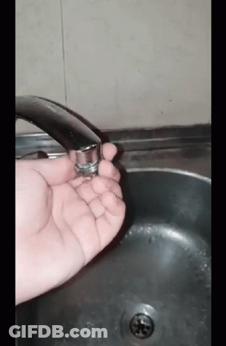 A Person Is Holding A Faucet In Their Hand In Front Of A Sink GIF