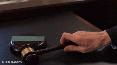 A Person Is Holding A Gavel In Front Of A Sign That Says Caratroops GIF