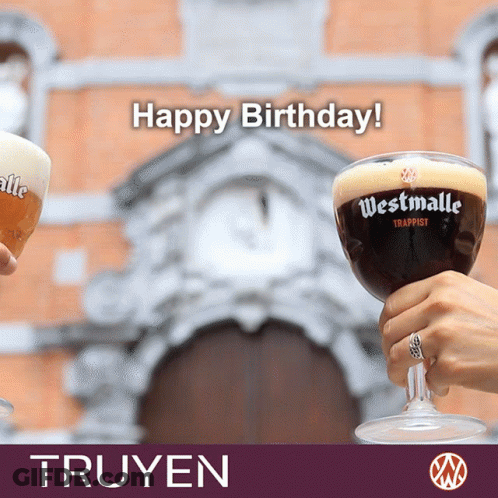 A Person Is Holding A Glass Of Westmalle Trappist In Front Of A Building GIF