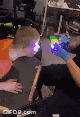 A Person Is Holding A Glow In The Dark Cube In Front Of A Child . GIF