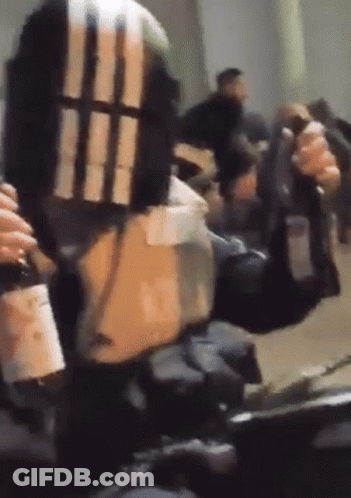 A Person Is Holding A Gun And A Bottle Of Wine In Their Hand . GIF