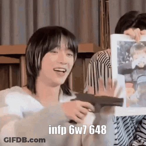A Person Is Holding A Gun And A Picture Of A Person In A Frame . GIF
