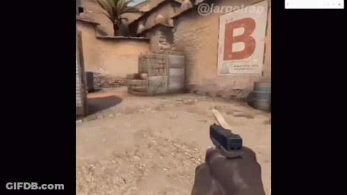 A Person Is Holding A Gun In Front Of A Sign That Says B On It . GIF