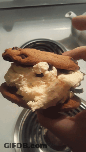 A Person Is Holding A Half Eaten Cookie With Whipped Cream And Chocolate Chips GIF