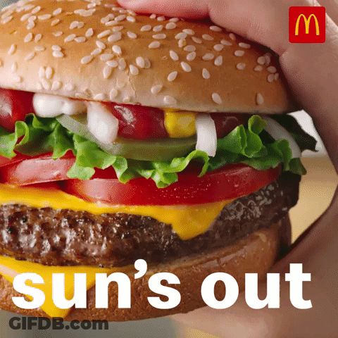 A Person Is Holding A Hamburger With The Words Sun 'S Out Behind Them GIF