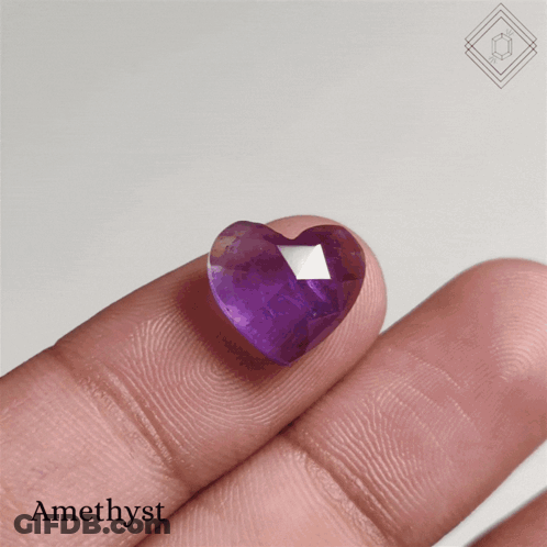 A Person Is Holding A Heart Shaped Amethyst In Their Hand GIF