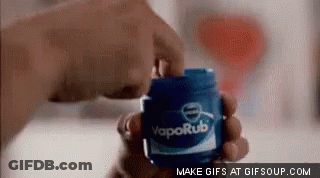 A Person Is Holding A Jar Of Vaporub . GIF