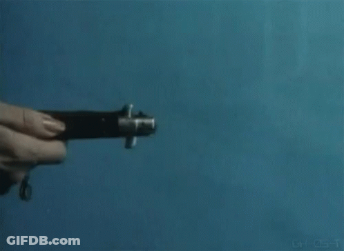 A Person Is Holding A Knife In Their Hand Against A Blue Wall . GIF