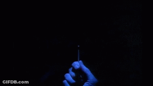 A Person Is Holding A Lighter In Front Of A Sign That Says `` Are You Afraid Of The Dark '' . GIF