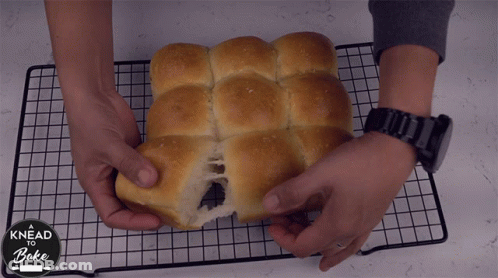 A Person Is Holding A Loaf Of Bread That Says Knead And Bake GIF