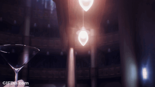 A Person Is Holding A Martini Glass In Front Of A Light GIF