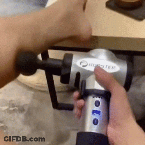 A Person Is Holding A Massage Gun In Their Hand And Using It On Their Arm . GIF