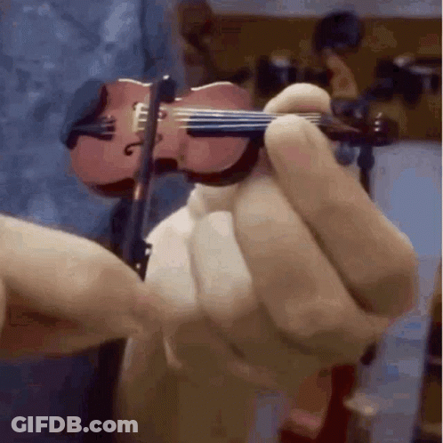 A Person Is Holding A Miniature Violin In Their Hand GIF