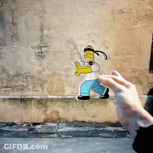 A Person Is Holding A Paper Cut Out Of Homer Simpson In Front Of A Wall That Says Efly GIF