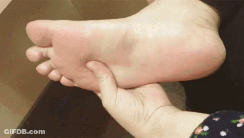 A Person Is Holding A Person 'S Foot In Their Hands . GIF
