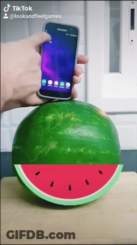 A Person Is Holding A Phone Over A Watermelon GIF