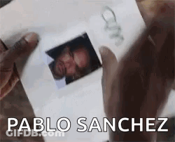 A Person Is Holding A Picture Of A Man In Their Hands . GIF