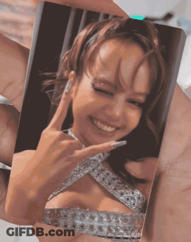 A Person Is Holding A Picture Of A Woman In A Silver Dress Making A Peace Sign GIF