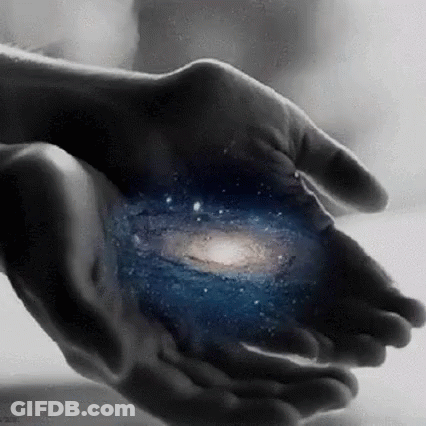 A Person Is Holding A Picture Of The Galaxy In Their Hands . GIF