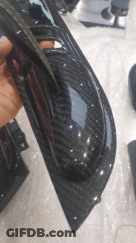 A Person Is Holding A Piece Of Black Carbon Fiber GIF