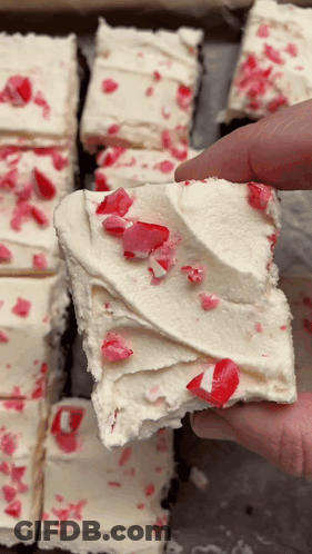 A Person Is Holding A Piece Of Cake With Candy Canes On Top GIF