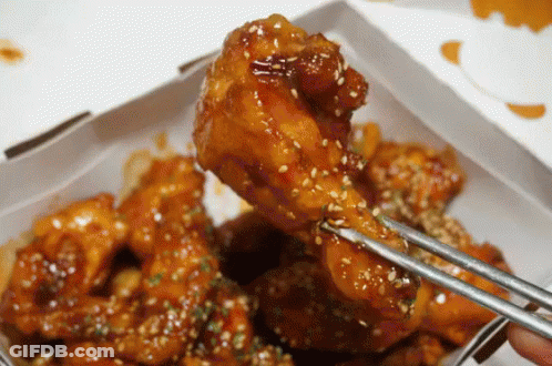 A Person Is Holding A Piece Of Chicken With Chopsticks GIF