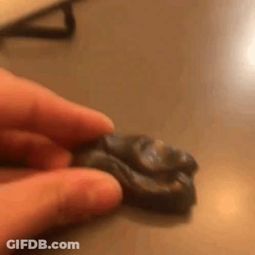 A Person Is Holding A Piece Of Clay In Their Hands . GIF