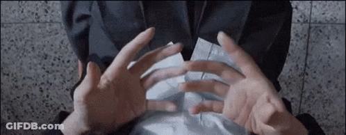 A Person Is Holding A Piece Of Paper Between Their Hands . GIF