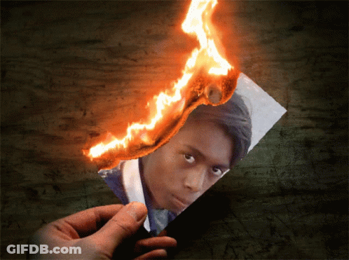 A Person Is Holding A Piece Of Paper That Is On Fire GIF