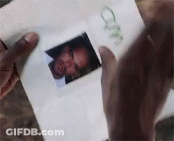 A Person Is Holding A Piece Of Paper With A Picture Of A Man 'S Face On It GIF