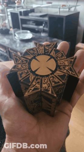 A Person Is Holding A Piece Of Wood With A Cross In The Center GIF