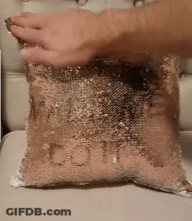 A Person Is Holding A Pillow With The Word Love Written On It . GIF