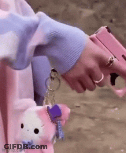 A Person Is Holding A Pink Gun In Their Hand While Wearing A Ring . GIF
