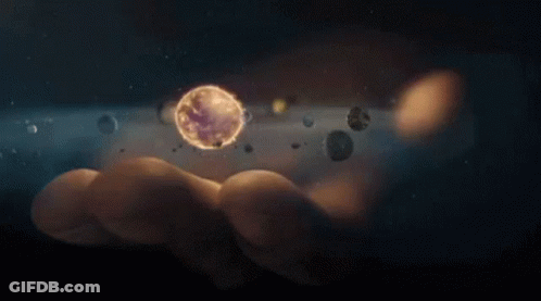 A Person Is Holding A Planet In Their Hand Surrounded By Other Planets . GIF