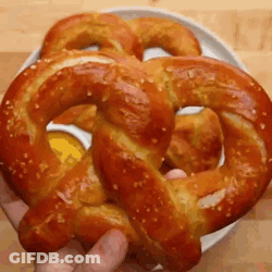 A Person Is Holding A Pretzel In Their Hand . GIF