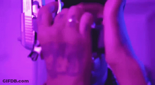 A Person Is Holding A Purple Object In Their Hands In A Purple Light . GIF